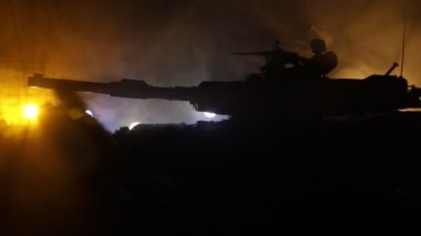 Zırhlı araç siluetinin savaş sisli arka planındaki savaş sahnesinin gece görüntüleri.