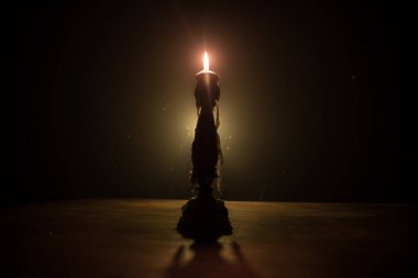 Tek yanan mum. Alevlerin ışığı ve akan mum, koyu arkaplan. Seçici odak