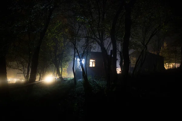 晚上在森林里有鬼的老房子或者是被遗弃的鬼屋 枯树森林里的古老神秘建筑 超现实的灯 可怕的万圣节概念 — 图库照片