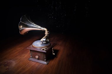 Müzik konsepti. Karanlık bir arka planda eski bir gramofon. Ahşap masanın üzerinde ton lambalı bir disk olan gramofon. Seçici odak