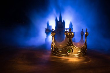 Tahta masanın üzerindeki güzel kraliçe ve kral tacının gösterişsiz görüntüsü. Eski model filtrelenmiş. fantezi ortaçağ dönemi. Seçici odaklanma. Renkli arka ışık