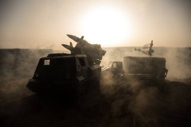 Yaratıcı sanat dekorasyonu. Gün batımında radar antenli mobil hava savunma aracı silueti. Roket fırlatıcı gökyüzüne nişan aldı ve saldırmaya hazır. Seçici odak