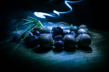 Sebze konsepti. Karanlıkta farklı soğanlar. Seçici odaklanma. Renkli arkaplan.