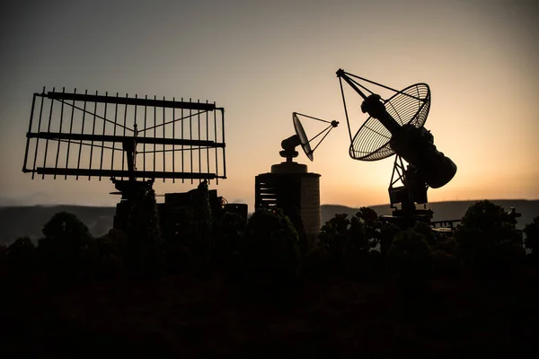 Space radar antenna on sunset. Silhouettes of satellite dishes or radio antennas against night sky. Creative artwork decoration. Selective focus