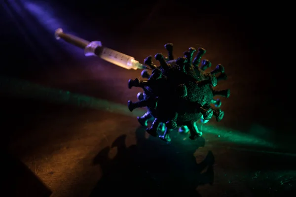 Corona virus Vaccine concept with syringe and green Corona virus novel miniature. Vaccine Concept of fight against coronavirus. Creative decoration with fog and backlight. Selective focus