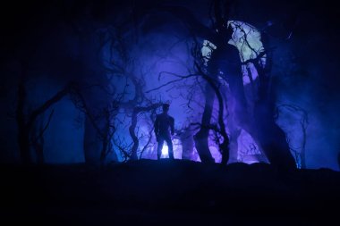 Kana susamış zombiler konsepte saldırıyor. Geceleri ölü ormanda yürüyen korkunç zombi silueti. Yaratıcı masa dekorasyonları. Seçici odak