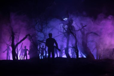 Zombi saldırısına karşı silahlı bir adam. Zombi kıyameti. Ormandaki bulanık zombilerin korkunç görüntüsü ve sisli, ürkütücü bulutlu gökyüzü. Korku Cadılar Bayramı konsepti.