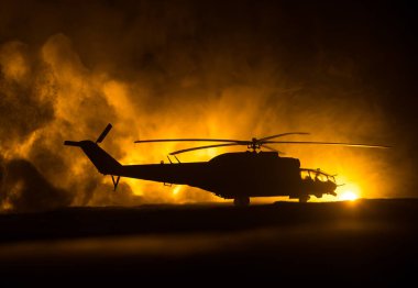 Askeri helikopterin silueti çatışma bölgesinden uçmaya hazır. Çölden başlayan sisli arka ışıklandırmalı helikopterle dekore edilmiş gece görüntüleri. Seçici odaklanma. Savaş konsepti