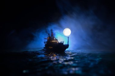 Savaş konsepti. Denizde gece savaşı sahnesi. Dramatik Ay dekoratif etkisi. Gece savaş gemisinin silueti. Minyatür yaratıcı masa dekorasyonu. Seçici odak