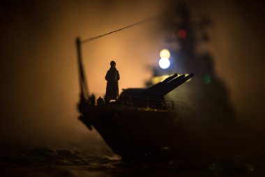 Savaş konsepti. Denizde gece savaşı sahnesi. Dramatik tonlu bulut etkisi. Gece savaş gemisinin silueti. Minyatür yaratıcı masa dekorasyonu. Seçici odak