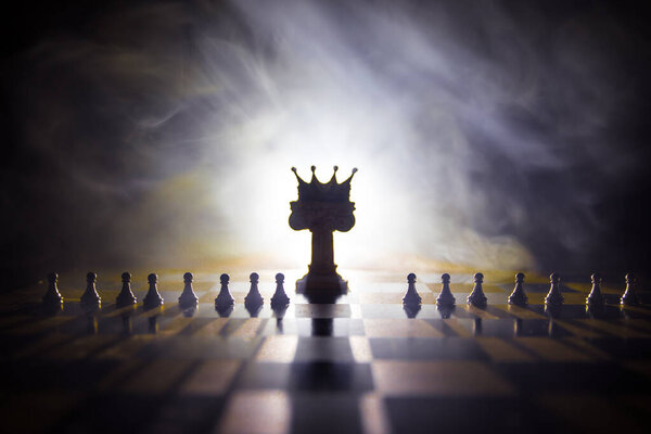 Beautiful crown miniature on chessboard. chess board game concept of business ideas and competition and strategy ideas concept. Chess figures on a dark background with smoke and fog. Selective focus