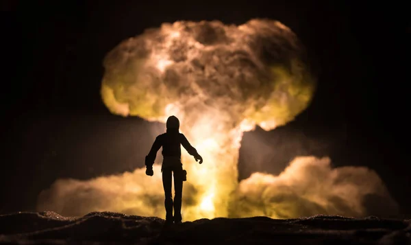 Nuclear war concept. Explosion of nuclear bomb. Creative artwork decoration in dark. Silhouette of a person against giant mushroom cloud of atomic explosion. Selective focus