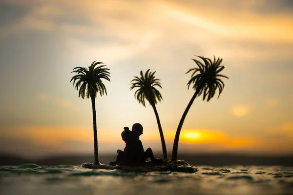 Romantic sunset scene. Fantasy landscape with little island with palms on sunset. Creative table decoration. Fantasy tropical beach. Selective focus.