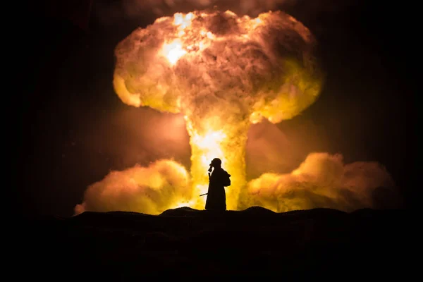 Nuclear war concept. Explosion of nuclear bomb. Creative artwork decoration in dark. Silhouette of soldier standing against giant mushroom cloud of atomic explosion. Selective focus