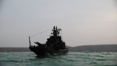 Savaş konsepti. Denizde gece savaşı sahnesi. Dramatik tonlu bulut etkisi. Gün batımında savaş gemisinin silueti. Minyatür yaratıcı masa dekorasyonu. Seçici odak