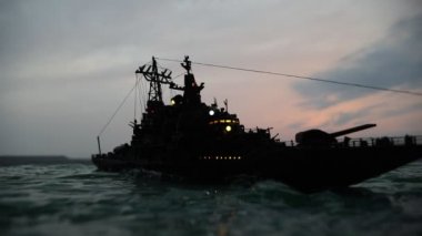 Savaş konsepti. Denizde gece savaşı sahnesi. Dramatik tonlu bulut etkisi. Gün batımında savaş gemisinin silueti. Minyatür yaratıcı masa dekorasyonu. Seçici odak