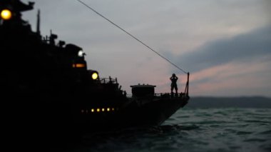Savaş konsepti. Denizde gece savaşı sahnesi. Dramatik tonlu bulut etkisi. Gün batımında savaş gemisinin silueti. Minyatür yaratıcı masa dekorasyonu. Seçici odak