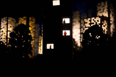 Yalnızlık kavramı, gece penceresinde kadın ve erkek silueti şeklinde. Beklentilerin, hayallerin ve kaderlerin sembolü. Şehir minyatürü ile yaratıcı dekorasyon. Seçici odak