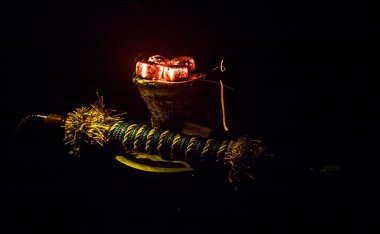 Shisha Konsepti. Siyah arkaplanlı shisha kasesinde sıcak nargile kömürü. Renkli ışıkları olan şık bir doğulu shisha. Seçici odak