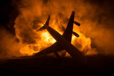 Uçak kazası. Düşen uçak yanıyor. Uçak yere çakıldı. Koyu renk arka planda oyuncaklarla süslenmiş. Uçak kazası konsepti. Seçici odak