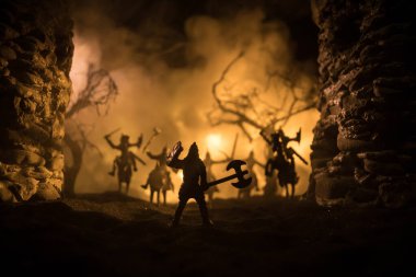 Süvari ve piyadelerle ortaçağ savaş sahnesi. Şekillerin siluetleri ayrı nesneler olarak, karanlık tonlu sisli arka planda ortaçağ şatosuyla savaşan savaşçılar arasında. Seçici odak