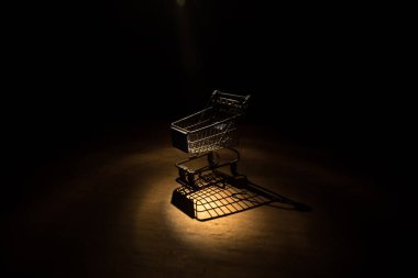 Karanlık, sisli arka planda fotokopi alanı olan boş bir alışveriş arabası. Finansal kriz konsepti. Seçici odak