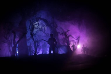 Zombi saldırısına karşı silahlı bir adam. Zombi kıyameti. Ormandaki bulanık zombilerin korkunç görüntüsü ve sisli, ürkütücü bulutlu gökyüzü. Korku Cadılar Bayramı konsepti.