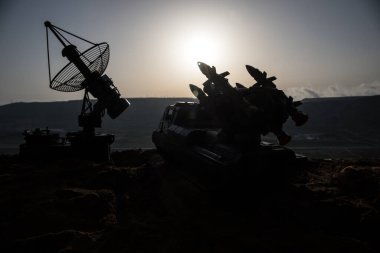 Yaratıcı sanat dekorasyonu. Gün batımında radar antenli mobil hava savunma aracı silueti. Roket fırlatıcı gökyüzüne nişan aldı ve saldırmaya hazır. Seçici odak