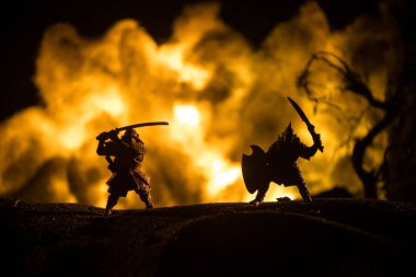 Süvari ve piyadelerle ortaçağ savaş sahnesi. Şekillerin siluetleri ayrı nesneler olarak, karanlık tonlu sisli arka planda ortaçağ şatosuyla savaşan savaşçılar arasında. Seçici odak