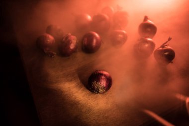 Sebze konsepti. Karanlıkta ahşap üzerine mor soğan. Seçici odaklanma. Renkli arkaplan.