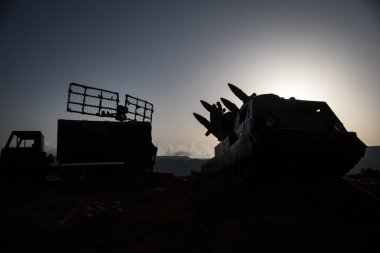 Yaratıcı sanat dekorasyonu. Gün batımında radar antenli mobil hava savunma aracı silueti. Roket fırlatıcı gökyüzüne nişan aldı ve saldırmaya hazır. Seçici odak
