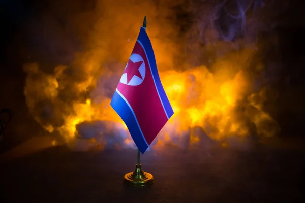 North Korea flag on burning dark background. Concept of crisis of war and political conflicts between nations. Selective focus