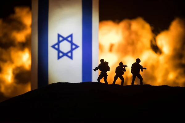 暗い背景に燃えるイスラエルの小さな旗 戦争の危機と国家間の政治的紛争の概念 イスラエルの旗に対する軍の戦闘シルエット 選択的焦点 — ストック写真