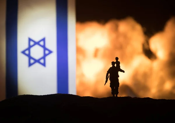 以色列小国旗在燃烧的黑暗背景 战争危机和国家间政治冲突的概念 武装士兵面对以色列国旗的轮廓 有选择的重点 — 图库照片
