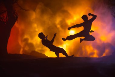 Yanan Orman 'da karate sporcuları gece dövüşü sahnesi. Karakter karatesi. Sanatçı figürü dekorasyonu. Spor konsepti. Işıkla süslenmiş sisli bir arka plan. Seçici odak