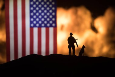 Yanan karanlık arka planda ABD bayrağı. Savaş krizi kavramı ve uluslar arasındaki siyasi çatışmalar. Amerikan bayrağına karşı silahlı asker silueti. Seçici odak
