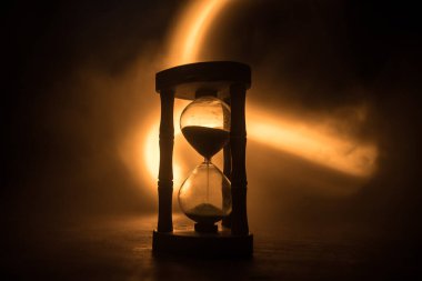 Zaman kavramı. Kum saatinin silueti koyu tonlu arka planda. Kopya alanı ile ilgili soyut bir kavram. Seçici odak