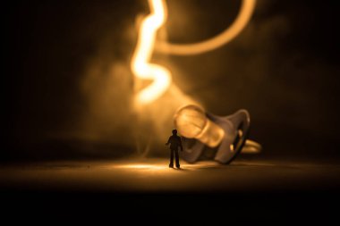 Yaratıcı bir kavram. Erkek silueti, ahşap masanın üzerinde yumuşak tonlu arka planda duran dev bebek emziğinde duruyor. Seçici odak