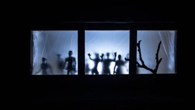 Sanat dekorasyonu. İçinde büyük pencereler ve zombiler olan eski bir ev. Penceredeki bulanık korkunç siluetler. Korku Cadılar Bayramı konsepti