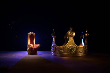 Güzel kralların ahşap masanın üzerinde taç giymesinin gösterişsiz görüntüsü. Eski model filtrelenmiş. fantezi ortaçağ dönemi. Seçici odaklanma. Renkli arka ışık