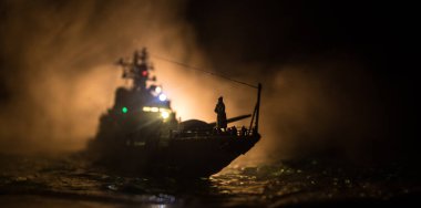Savaş konsepti. Denizde gece savaşı sahnesi. Dramatik tonlu bulut etkisi. Gece savaş gemisinin silueti. Minyatür yaratıcı masa dekorasyonu. Seçici odak