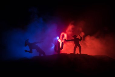 Batı konsepti. Geceleri kovboylar arası savaş. Ölümüne düello. Seçici odak noktasında rengarenk sisli arkaplan üzerine yaratıcı sanat dekorasyonu