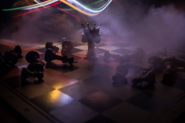 Satranç tahtasında güzel bir taç minyatürü. Satranç masası iş fikirleri, rekabet ve strateji fikirleri konsepti. Duman ve sisli karanlık bir arka planda satranç figürleri. Seçici odak