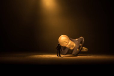 Yaratıcı bir kavram. Erkek silueti, ahşap masanın üzerinde yumuşak tonlu arka planda duran dev bebek emziğinde duruyor. Seçici odak