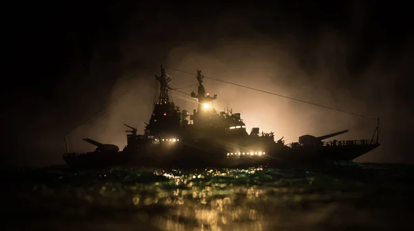 War concept. Night battle scene at sea. Dramatic toned clouds effect. Silhouette of the battle ship in night. Miniature creative table decoration. Selective focus