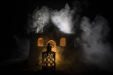 Gece parlayan yanan mumlu süs Arap feneri. Arka planda gerçekçi bir cami minyatürü var. Kutlama kartı, Müslüman kutsal ayı için davetiye Ramazan Kareem. Seçici odak