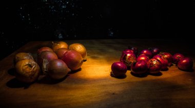 Sebze konsepti. Karanlıkta farklı soğanlar. Seçici odaklanma. Renkli arkaplan.