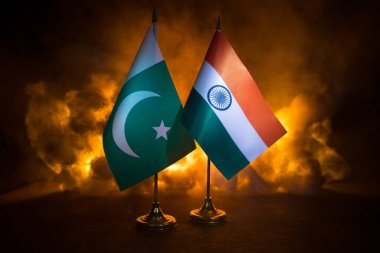 Hindistan ve Pakistan yanan karanlık arka planda küçük bir bayrak. Savaş krizi kavramı ve uluslar arasındaki siyasi çatışmalar. Seçici odak