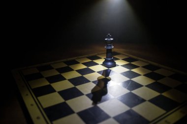 Satranç tahtasında güzel bir taç minyatürü. Satranç masası iş fikirleri, rekabet ve strateji fikirleri konsepti. Duman ve sisli karanlık bir arka planda satranç figürleri. Seçici odak