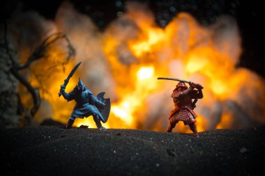 Süvari ve piyadelerle ortaçağ savaş sahnesi. Şekillerin siluetleri ayrı nesneler olarak, karanlık tonlu sisli arka planda ortaçağ şatosuyla savaşan savaşçılar arasında. Seçici odak